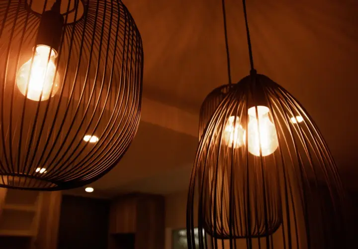 Trzy nowoczesne lampy wiszące z metalowymi kloszami i żarówkami Edisona.