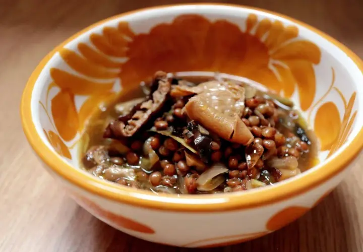 Un reconfortante plato de lentejas con boletus, servido en un cuenco decorado con motivos naranjas.