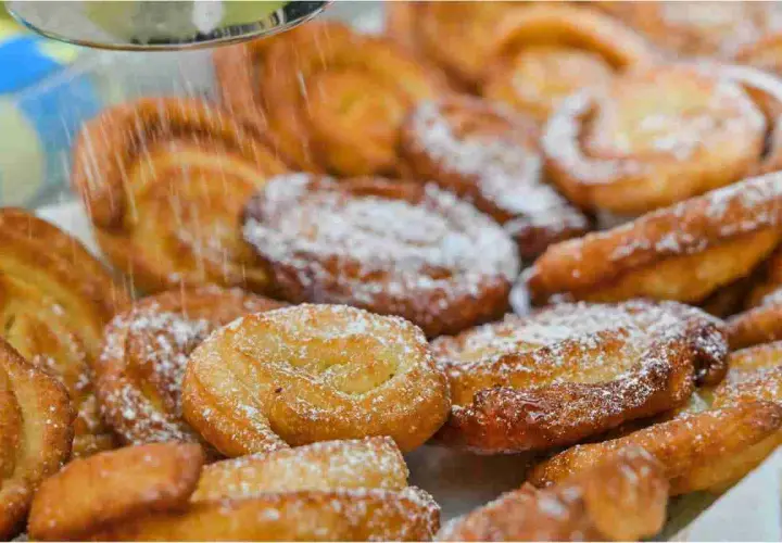 Dolci fritti cosparsi di zucchero a velo, perfetti per il Carnevale. Sembrano deliziosi limoncini, pronti per essere gustati.
