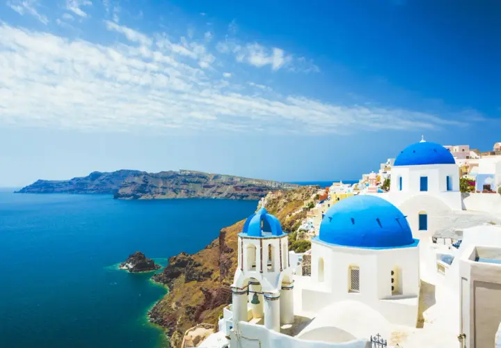 Santorini, gdzie leży Grecja, zachwyca białymi domkami i błękitnymi kopułami kościołów nad morzem.