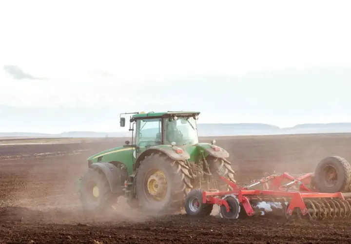Zielony traktor orze pole. To symbol przekazania gospodarstwa rolnego, które pozwala na opiekę nad rodzicami i dalszy rozwój.