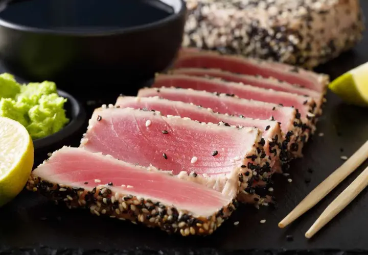 Trancio di tonno scottato con sesamo, pronto per gustose ricette. Accompagnato da wasabi, lime e salsa di soia.