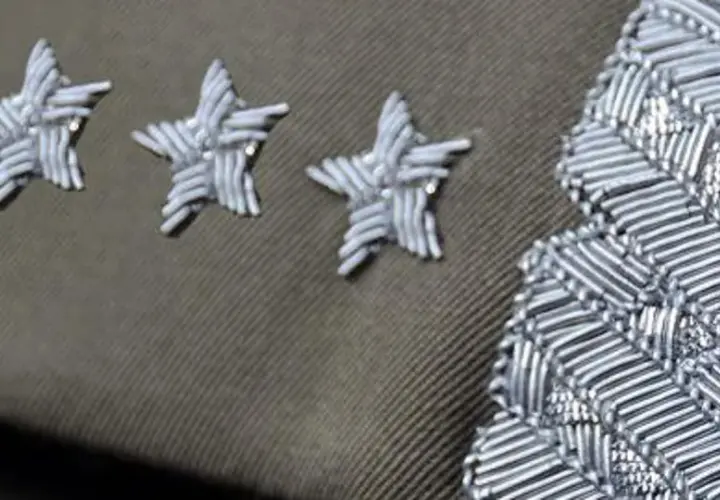 Trzy gwiazdki w wojsku, symbol wysokiej rangi, zdobią mundur obok ozdobnego naramiennika.