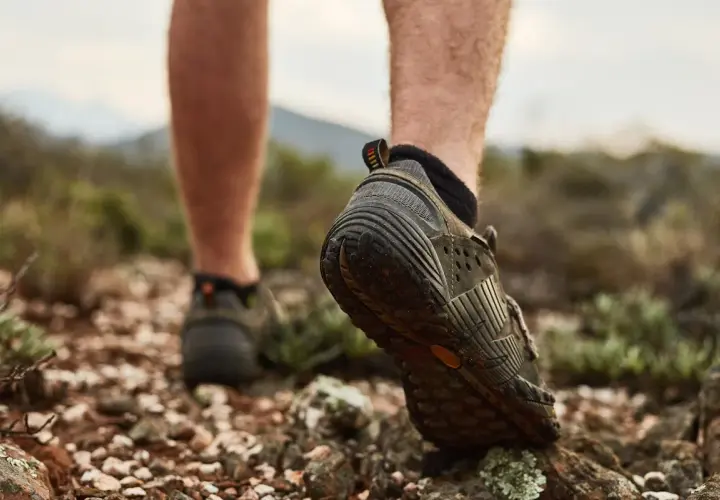 Niski profil butów trekkingowych, z widoczną wysokością cholewki, podczas marszu po kamienistym, suchym terenie.