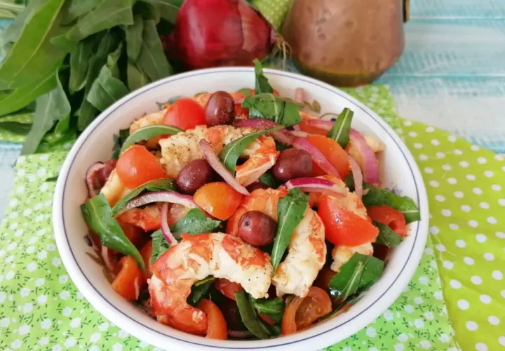 Deliziosa catalana di gamberi con pomodorini, olive, cipolla rossa e rucola, un piatto fresco e colorato.