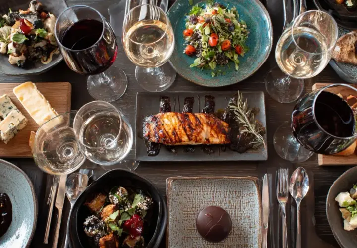 Un verre de pinot noir avec un plat de poisson grillé, accompagné de salades, fromages et desserts.