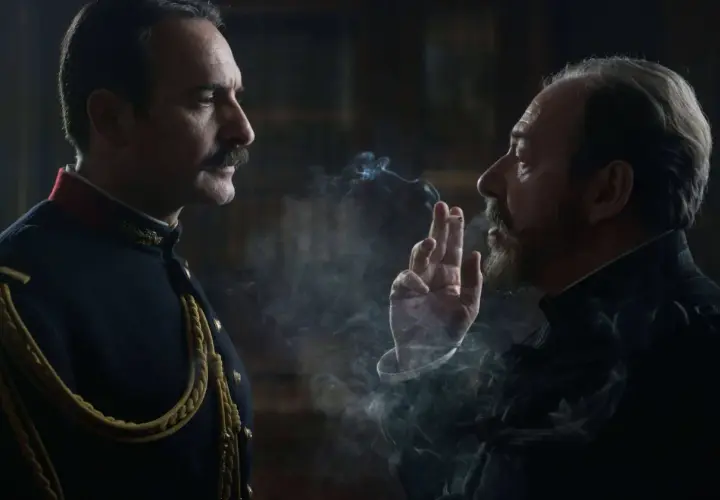 Dwaj mężczyźni w historycznych strojach, jeden w mundurze, drugi z papierosem, w kłębach dymu. Scena z filmu Polańskiego.