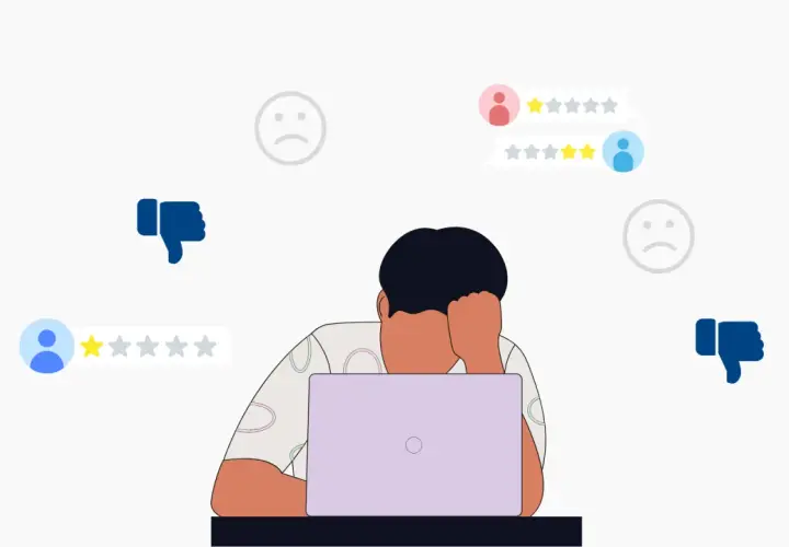 Persona frustrata davanti al laptop, circondata da recensioni negative e pollici in giù. Impara come rispondere alle recensioni negative per migliorare la tua reputazione online.