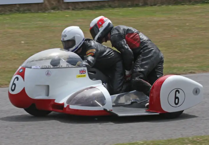 Dos pilotos en un sidecar de carreras, uno conduciendo y el otro en la silla lateral. El número 6 en el sidecar. William Dunlop, un nombre asociado con la velocidad.