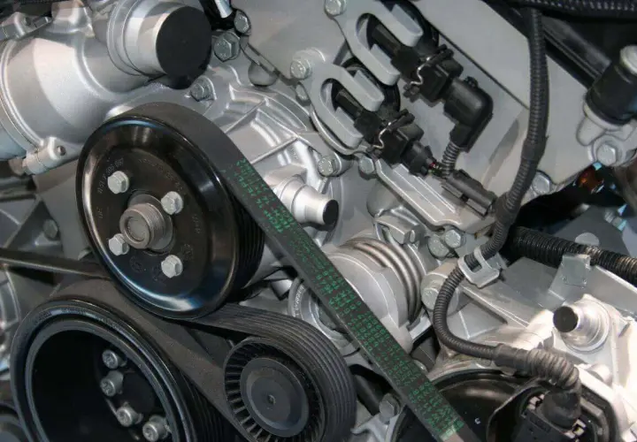 Detalle del motor de un coche, mostrando la polea y la correa de distribución.
