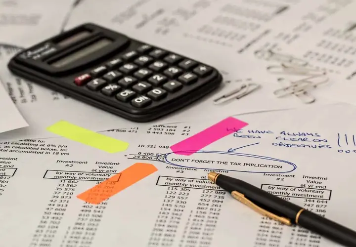 Kalkulator, notatki i dokumenty finansowe. Na jednym z nich widnieje napis "DON'T FORGET THE TAX IMPLICATION", sugerujący rozważania nad **podatkiem rolnym**.