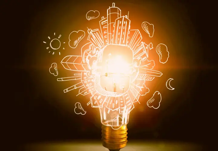 Bombilla encendida con dibujos de ciudad, sol y luna. Representa la diferencia entre potencia y energía, la chispa de una idea.