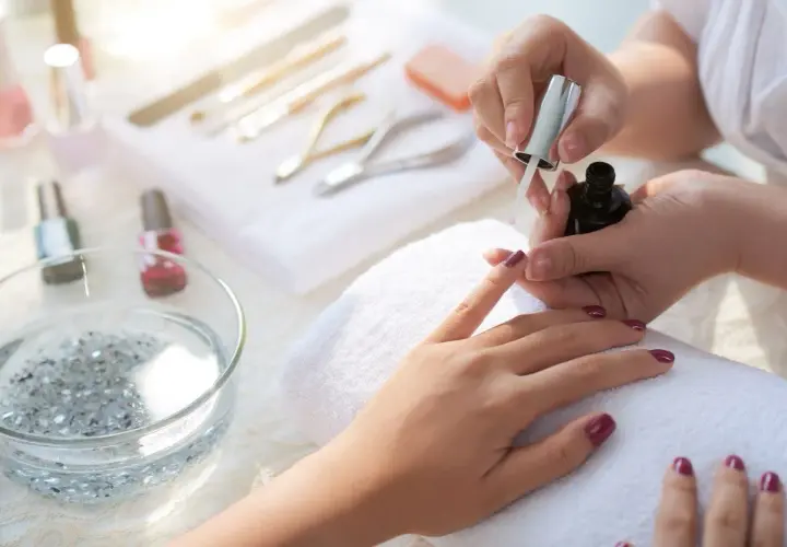 Manicure tytanowy krok po kroku: aplikacja lakieru na paznokcie, narzędzia do stylizacji w tle.