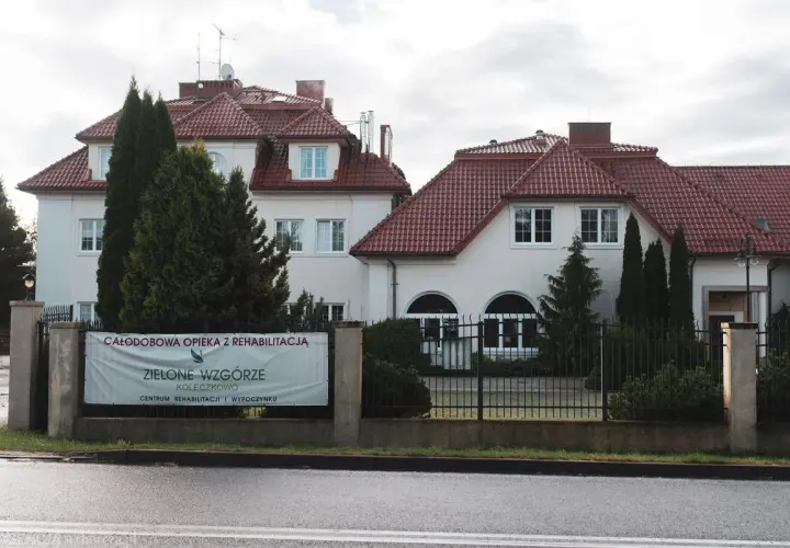 Budynek z czerwonym dachem i banerem "Zielone Wzgórze".