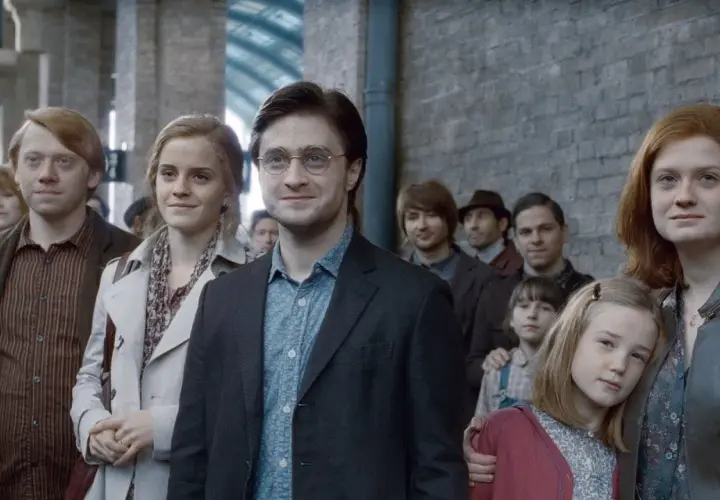 Harry Potter, z charakterystyczną blizną, stoi w tłumie na dworcu. Obok niego Hermiona i Ron.