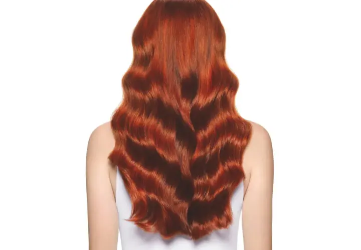Una melena ondulada y brillante de pelo cobrizo natural, con reflejos dorados que capturan la luz.