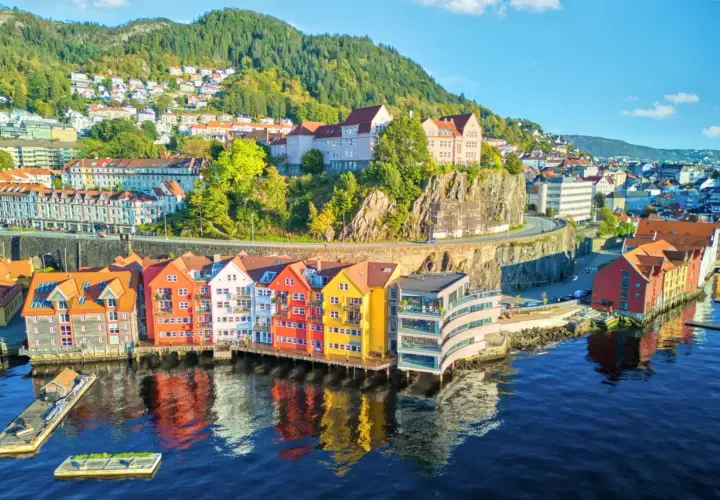 Kolorowe kamienice nad wodą, wzgórza z domkami w tle – to malownicza Norwegia latem.