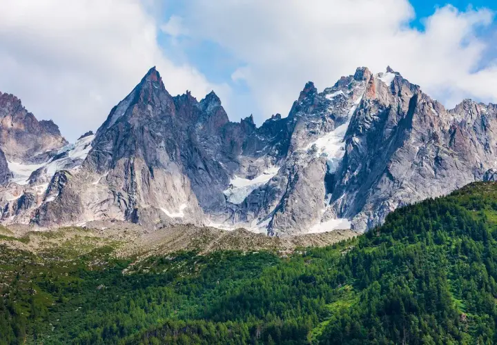 Majestatyczne szczyty Mont Blanc latem, z zielonymi zboczami i resztkami śniegu.
