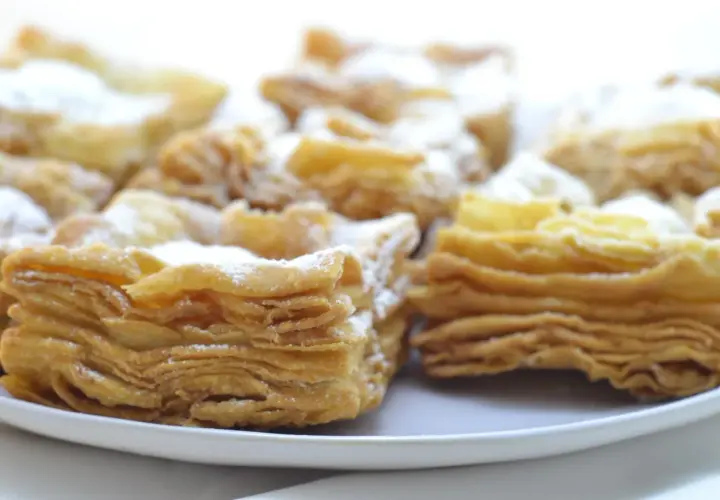 Deliciosos pastelitos de hojaldre con azúcar glas. El hojaldre, con sus capas crujientes y doradas, invita a probarlos.