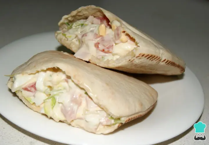 Dos deliciosos bocadillos de pan pita rellenos de ensalada cremosa, jamón y huevo.