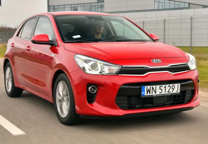Czerwony Kia Rio 4 w ruchu, z kierowcą za kierownicą.