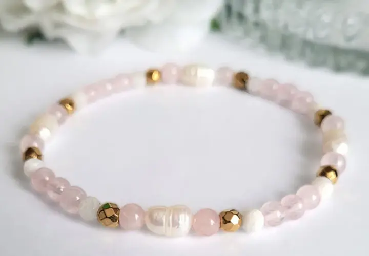 Delikatna bransoletka z koralików kwarc różowy, pereł i złotych elementów. Symbol miłości i harmonii.