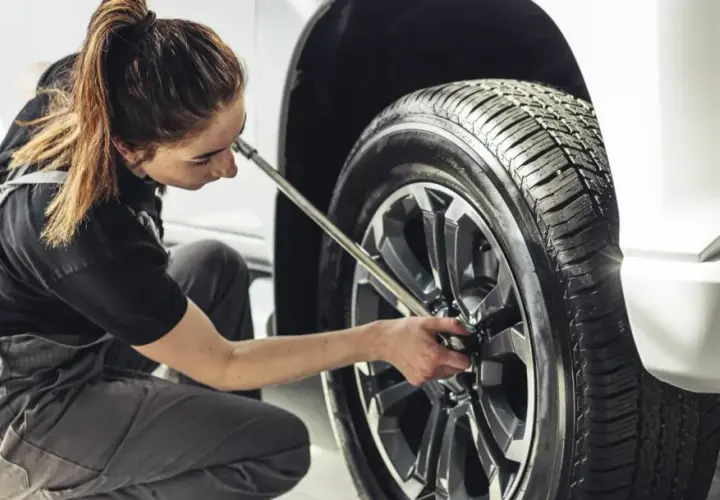 Mecánica trabajando en el cambio de ruedas de un coche.