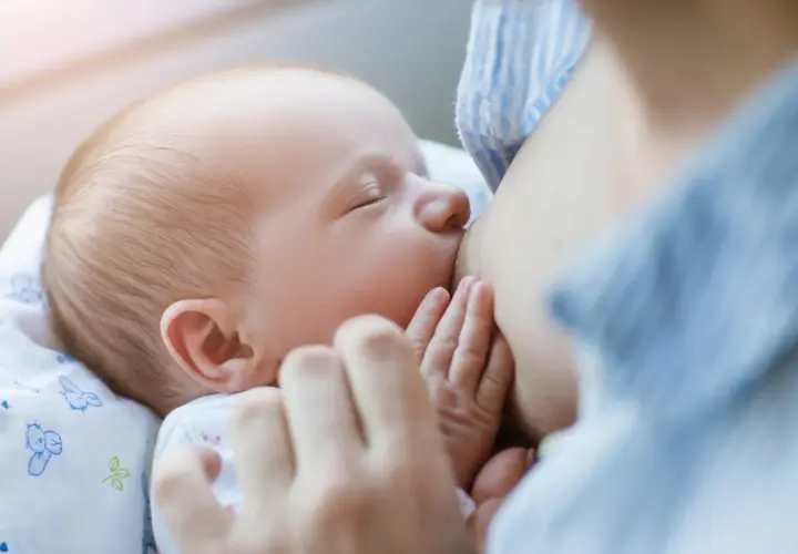 Malutkie rączki otulają pierś mamy. Karmienie piersią to piękny moment, w przeciwieństwie do palenia papierosów, które szkodzi dziecku.