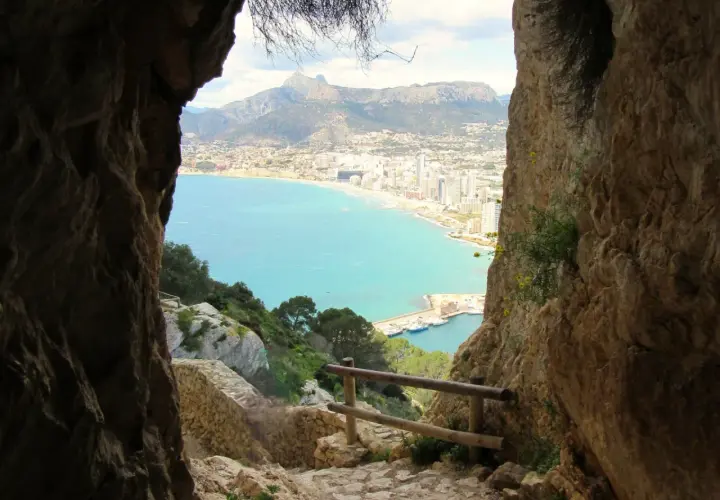 Camino rocoso para subir al Peñón de Ifach, con vistas al mar turquesa y la ciudad.