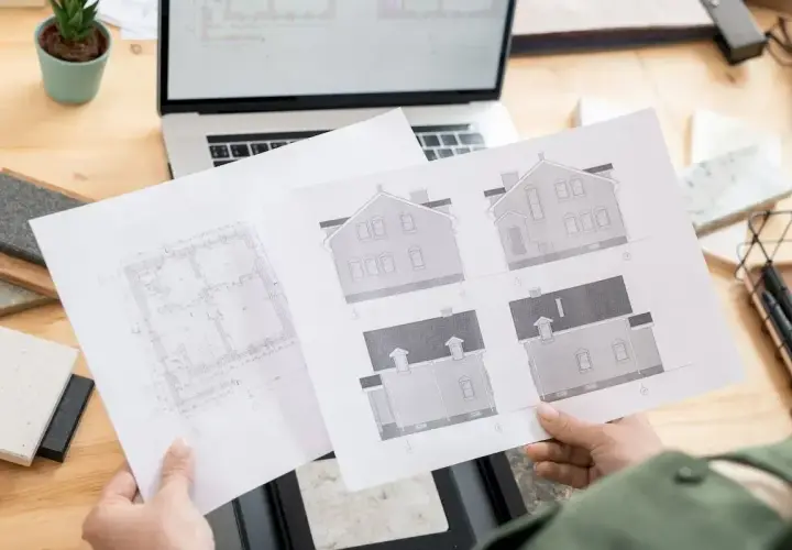 Architekt analizuje plany domu, zastanawiając się, ile trzeba czekać na pozwolenie na budowę.