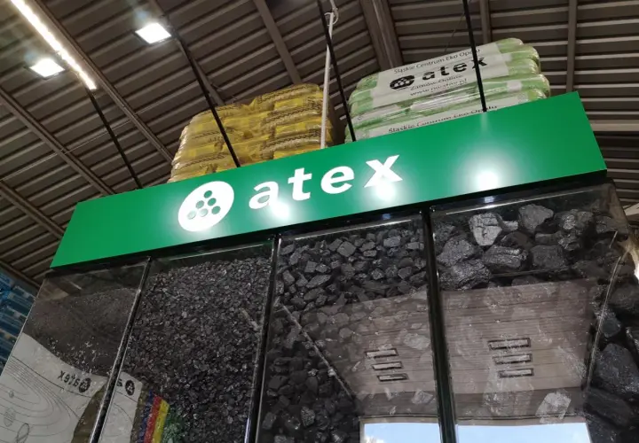 Atex Pilchowice: ceny węgla. Różne rodzaje węgla w gablotach, nad nimi logo Atex i paczki z ekogroszkiem.