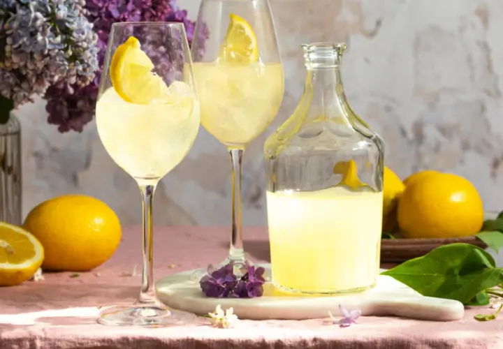 Erfrischender Limoncello Spritz mit Zitronenscheiben, Eis und Flieder.