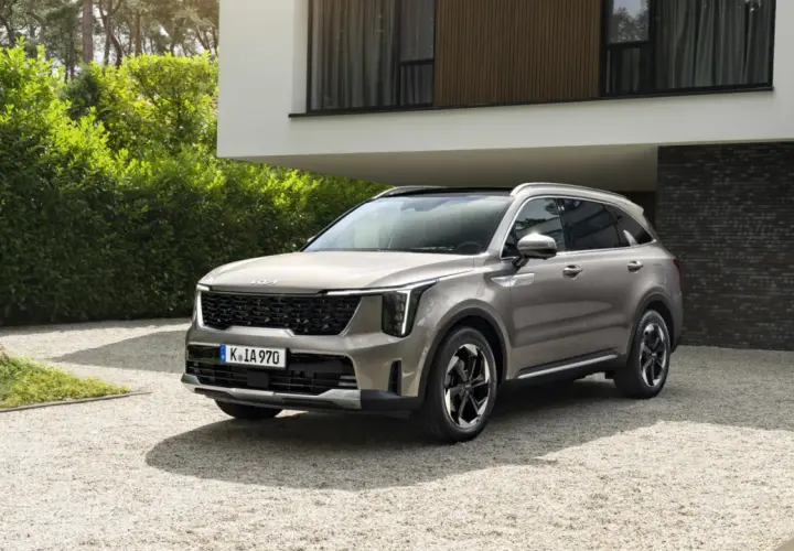 SUV Kia Sorento color sabbia, un esempio delle migliori auto benzina, parcheggiata su ghiaia davanti a una casa moderna.