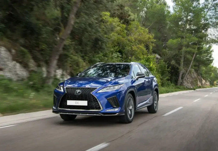 Niebieski Lexus RX 450h jedzie po krętej drodze wśród zieleni.