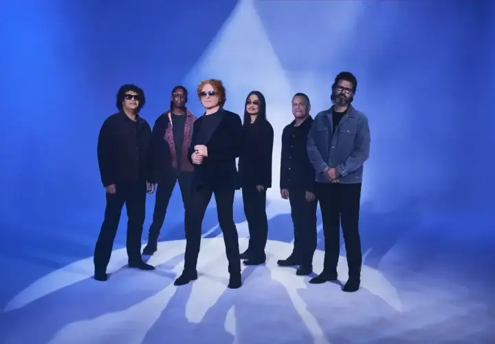 Zespół Simply Red na niebieskim tle, gotowy do koncertu.