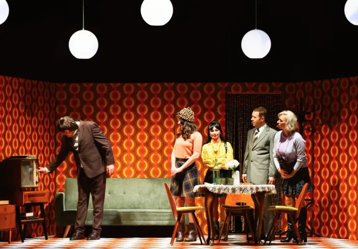 Scena z życia w polskich teatrach: mężczyzna przy starym telewizorze, kobiety w modnych strojach i elegancki pan.