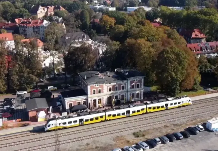 Nowoczesny szynobus pokonuje trasę Wrocław - Trzebnica, mijając malowniczą stację i jesienne drzewa.