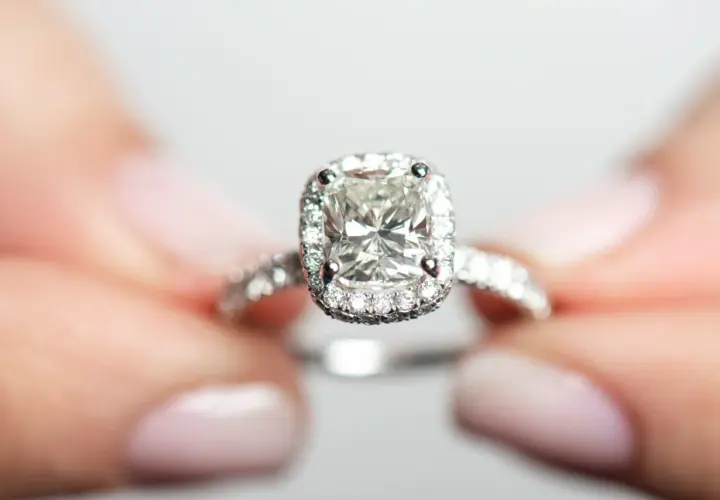 Ein funkelnder Verlobungsring mit einem großen Diamanten im Zentrum, umgeben von kleineren Steinen. Die Reinheit der Diamanten ist beeindruckend, fast wie eine Tabelle der Perfektion.