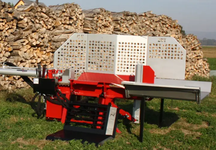 Roter Holzspalter mit 20T-Aufschrift, bereit für das nächste Holzspalter-Angebot. Im Hintergrund ein großer Stapel gespaltenes Holz.