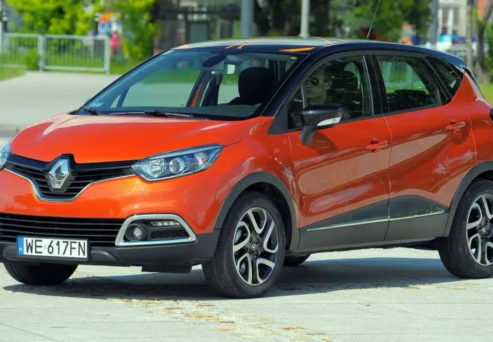 Pomarańczowy Renault Captur 2015 z czarnym dachem i felgami stoi na placu.