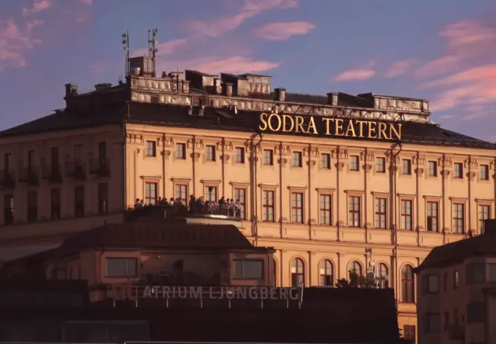 Södra Teatern, en ikonisk byggnad vid Mosebacke, badar i kvällssolens rosa sken.