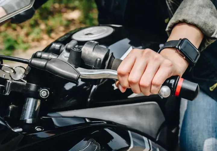 Mano sujetando el manillar de una moto, lista para accionar el freno motor.