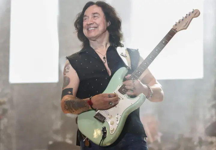 Jan Borysewicz z Lady Pank gra na gitarze, uśmiechając się do publiczności.