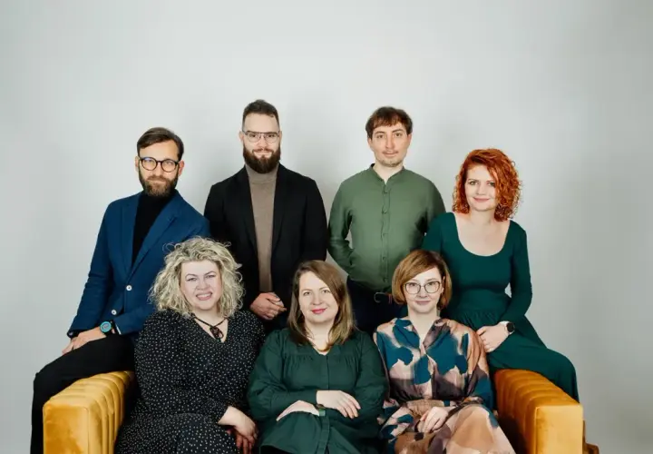 Grupa siedmiu psychoterapeutów, cztery kobiety i trzech mężczyzn, pozuje do zdjęcia na kanapie.