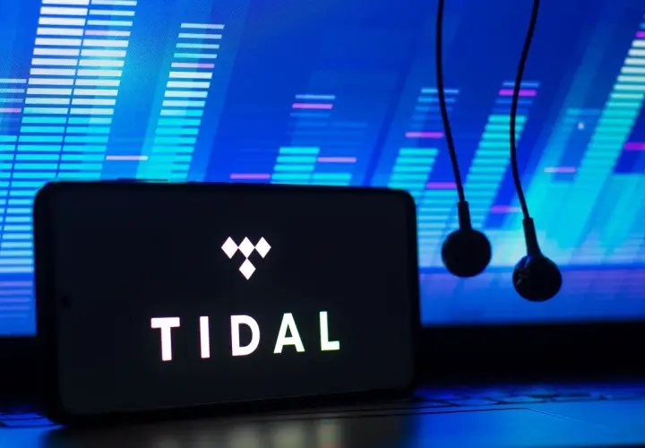 Smartfon z logo TIDAL i słuchawkami na tle wykresu dźwiękowego.