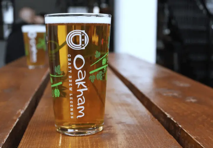 Verre de bière blonde Oakham sur table en bois. Le taux de sulfate dans l'eau est idéal pour cette boisson artisanale.