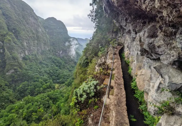 Ein schmaler Weg entlang eines Kanals führt durch eine Schlucht auf Madeira. Die Levadas Madeira sind ein beeindruckendes Wandererlebnis.