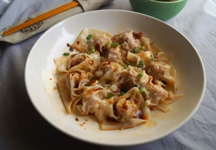 Pyszne pierożki wonton polane pikantnym sosem, posypane szczypiorkiem i sezamem. Ciasto do wontonów jest cienkie i delikatne.