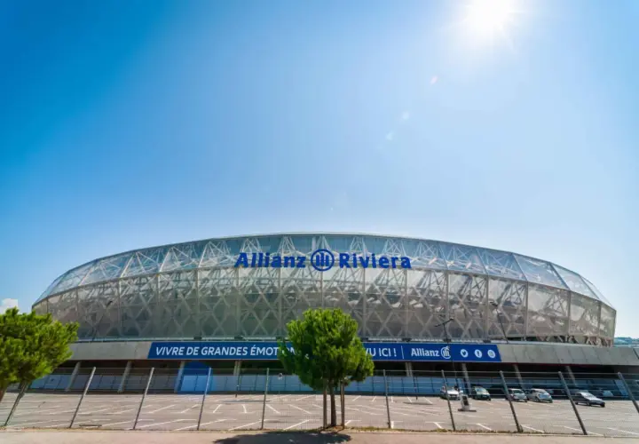 Nowoczesny stadion Allianz Riviera w Nicei, z charakterystycznym, przeszklonym dachem i niebieskim napisem.