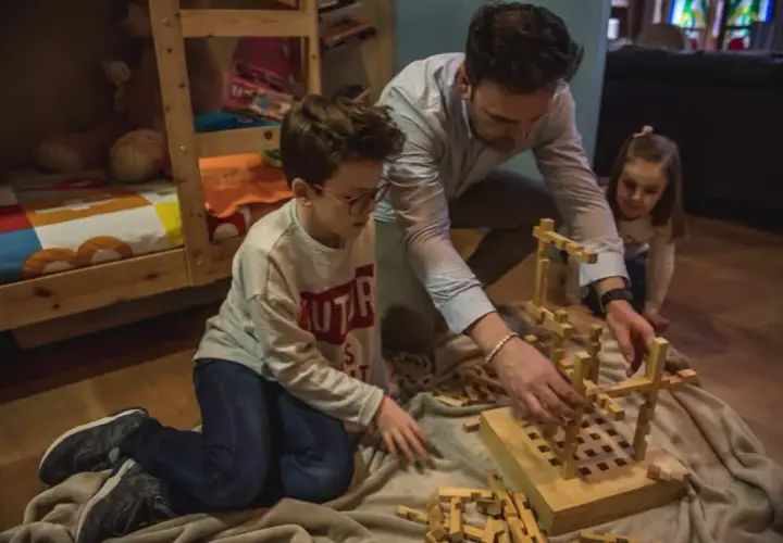 Padre e hijos construyen con bloques de madera, creando sus propios juguetes Waldorf caseros.